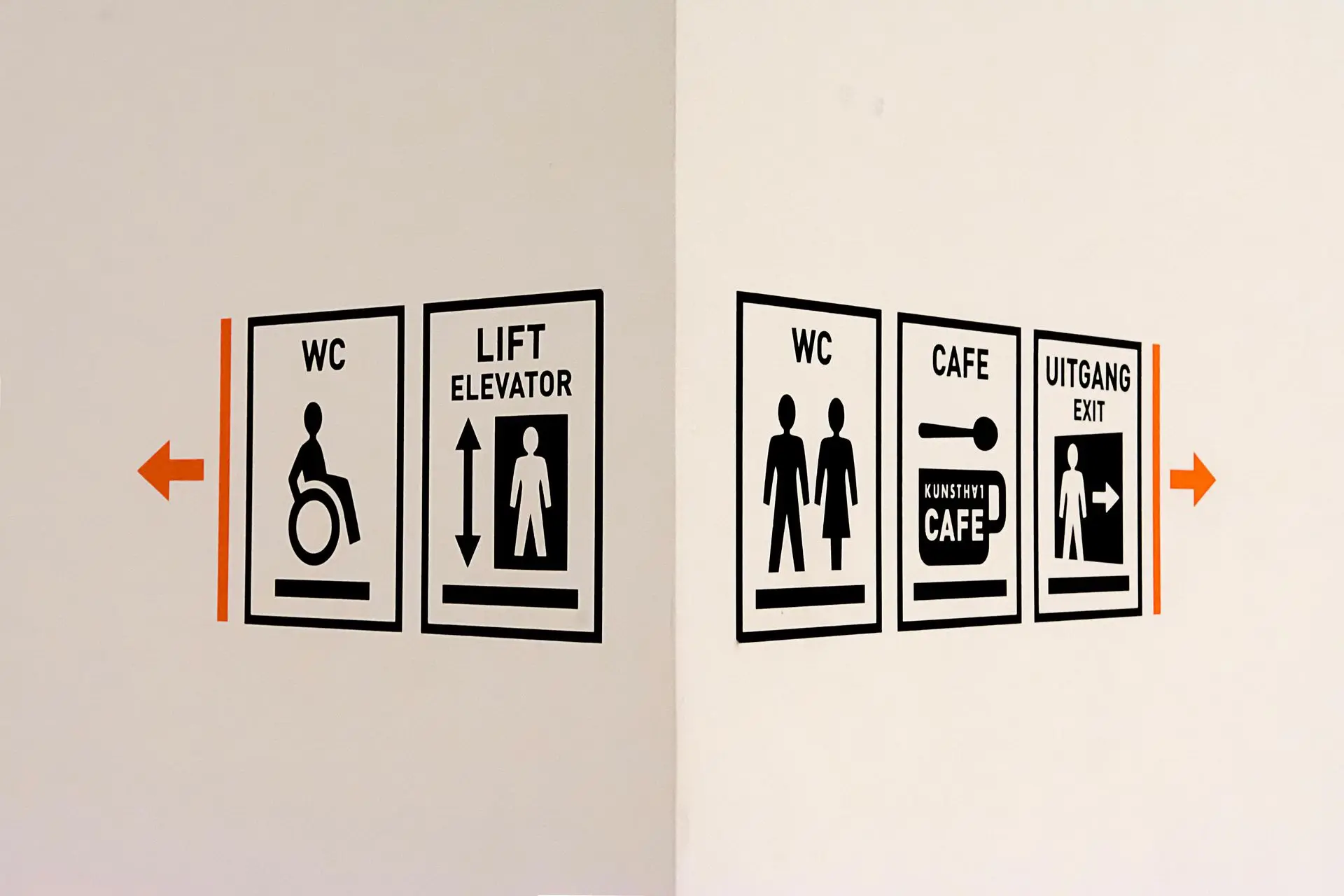 Directional signage indicating restrooms, elevator, café, and exit with arrows pointing left and right.