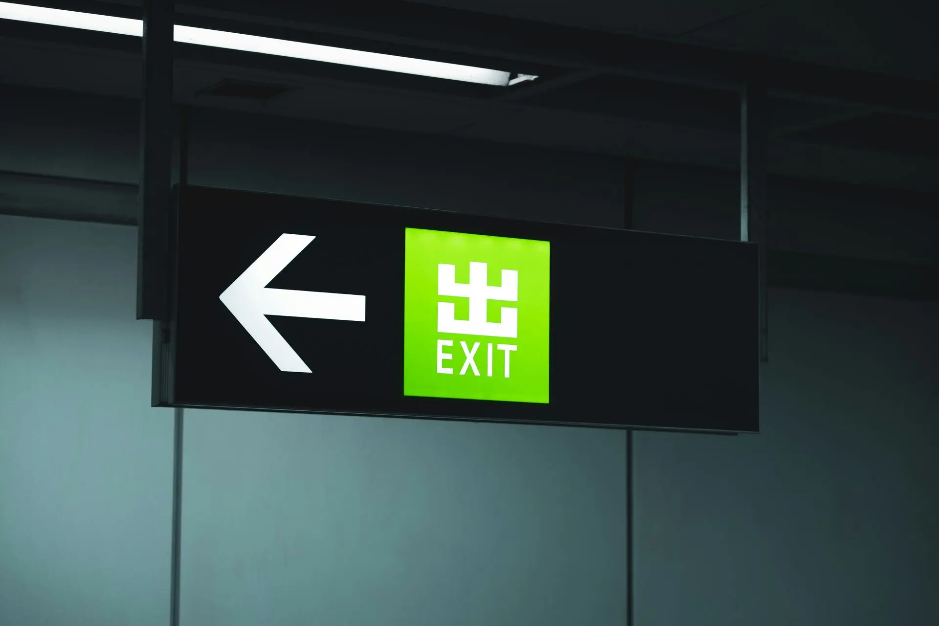  Illuminated exit sign with a green background and left arrow, prominently displaying the word "EXIT."