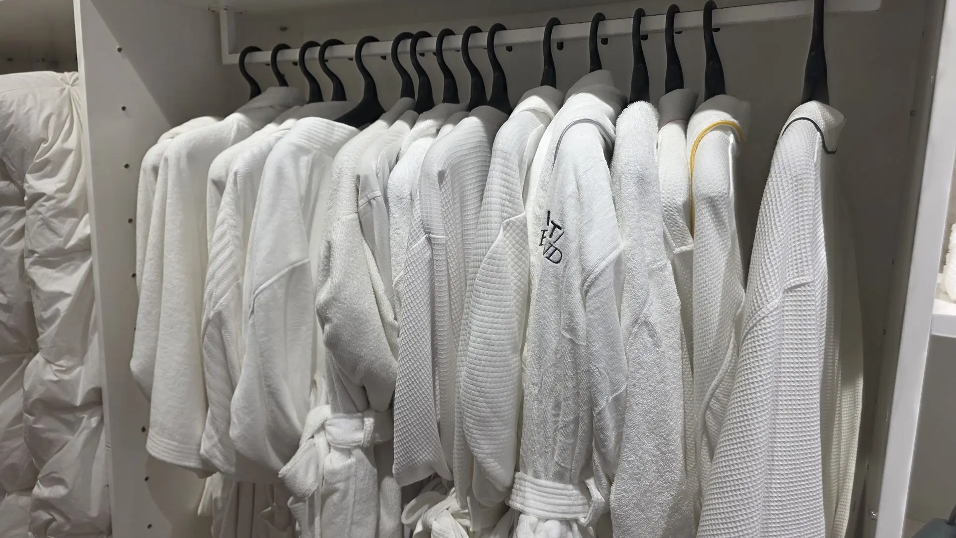 White luxury hotel bathrobes hanging on a closet rack provided by World’s OS&E in China.