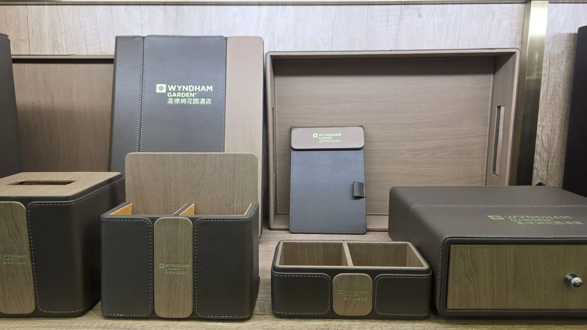 Branded Wyndham Garden hotel room accessories including a leather tissue box, notepad holder, stationery organizer, and wooden tray