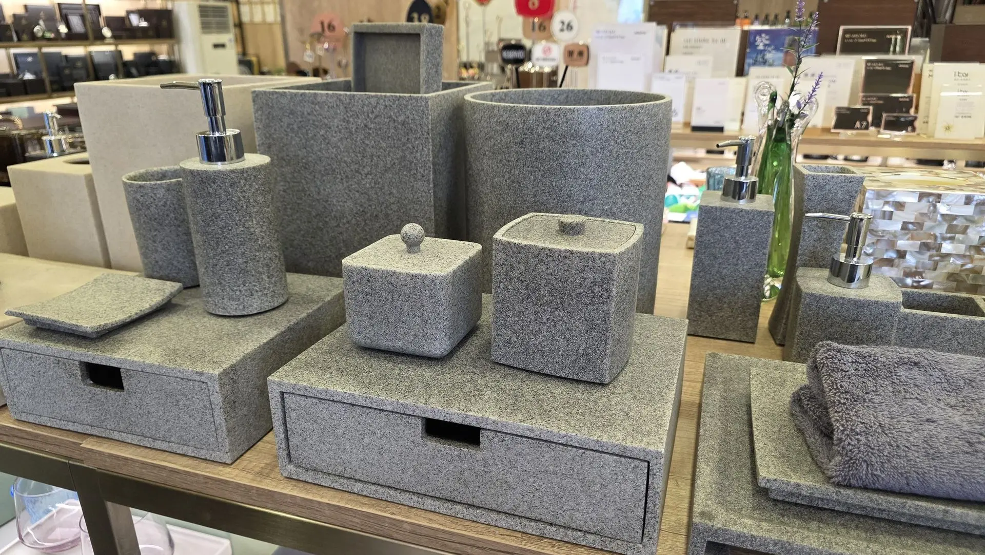 A collection of bathroom accessories including soap dispensers, trays, and storage boxes made of gray textured resin with a faux stone finish.