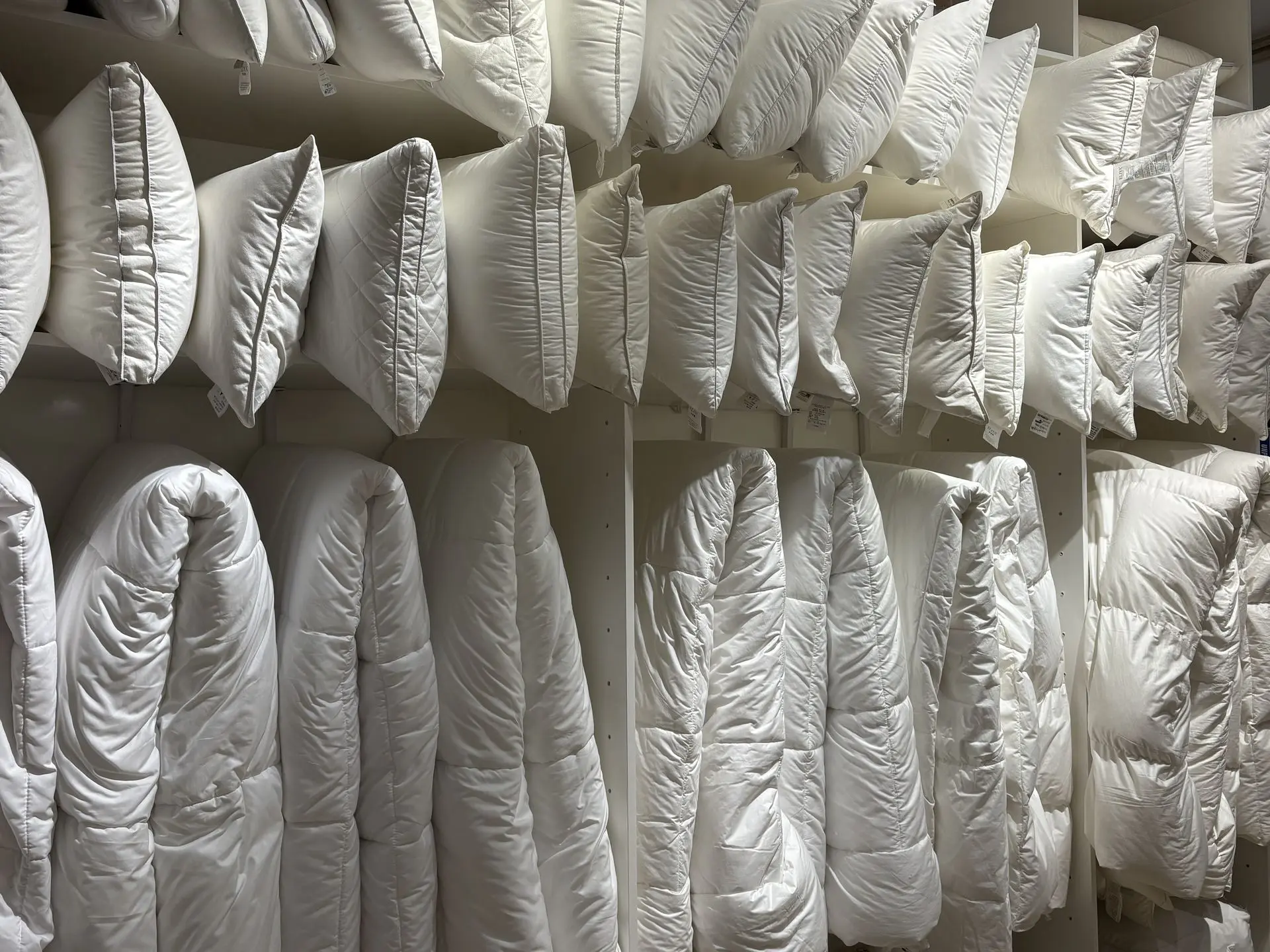 Display of white down pillows and comforters from a China os&e hospitality bedding supplier.