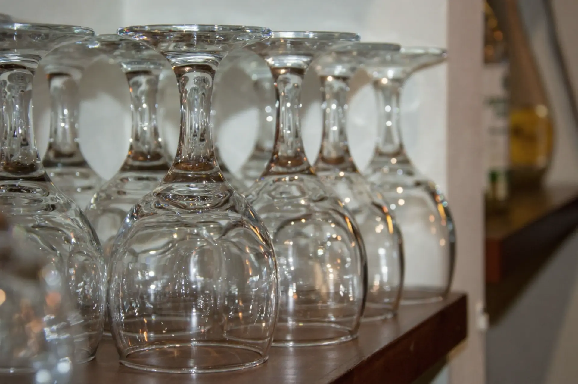 Durable Glassware for Hospitality - China OS&E Solutions Row of upside-down stemmed glassware on a shelf, part of high-quality China OS&E hospitality supplies.