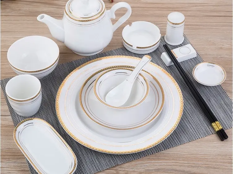 Premium China OS&E Porcelain Tableware Collection White and gold China OS&E luxury bone china dinnerware set including teapot, bowls, plates, and gold-tipped chopsticks on a grey placemat.