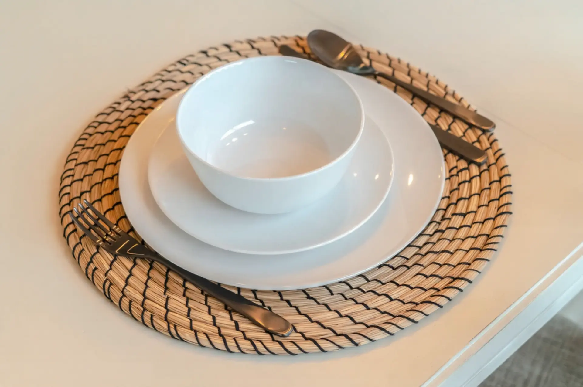 Durable White China Melamine Dinnerware Set Set of white China melamine dinnerware including a bowl and plates on a woven placemat with black cutlery.