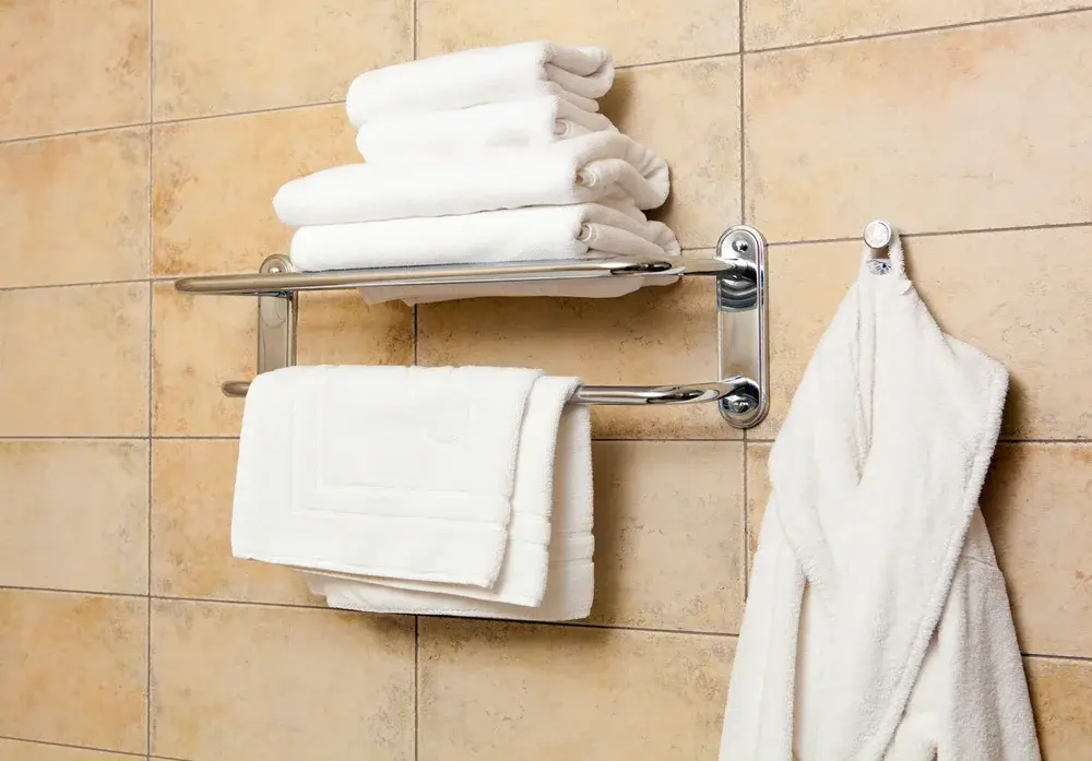 Stainless steel guestroom bathroom towel rack from China featuring anti-rust coating and folded white towels.