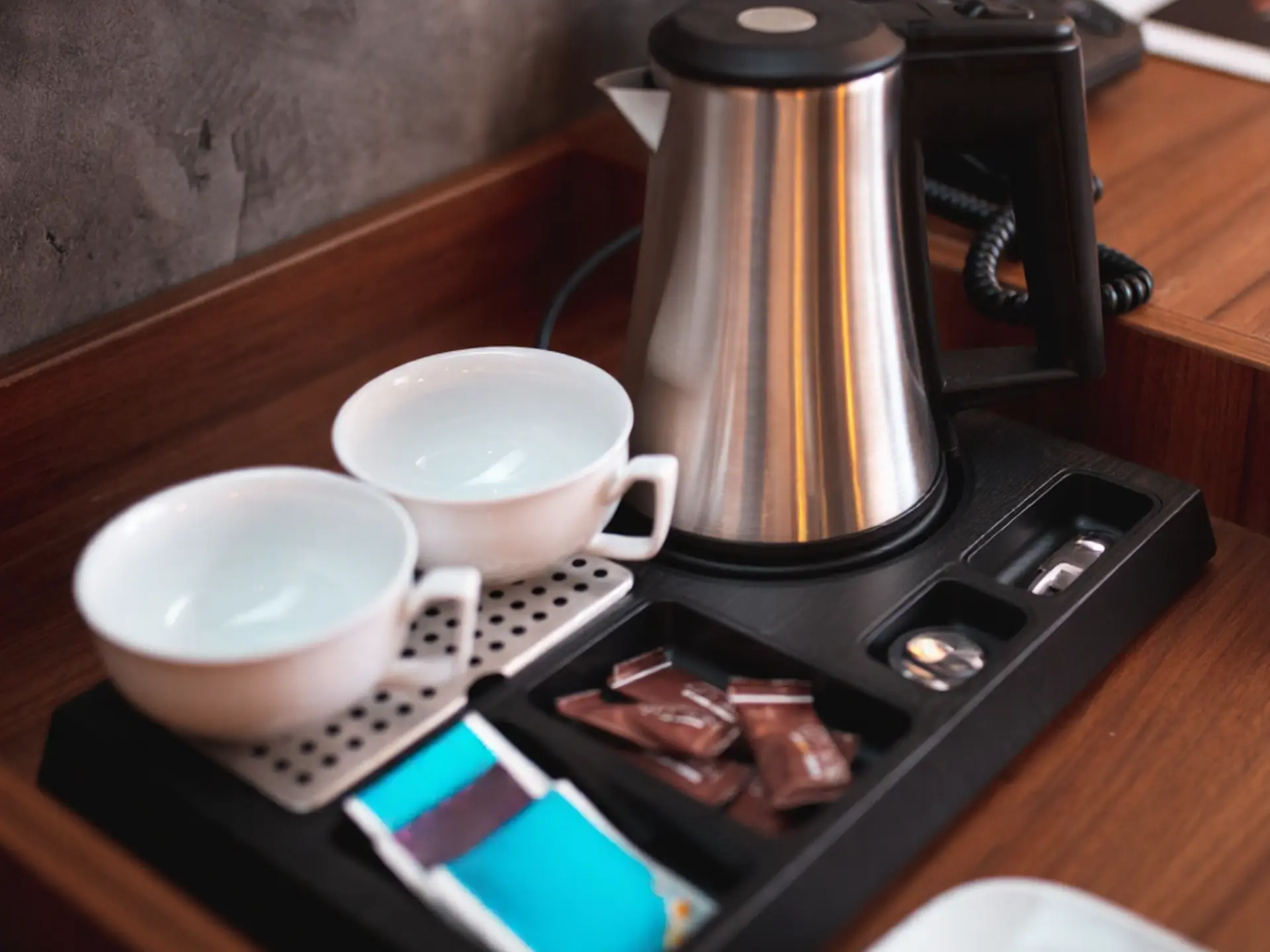 Hotel Guestroom Electric Kettle and Welcome Tray Set - OS&E China Stainless steel electric kettle on a black welcome tray with ceramic cups and condiment sachets, premium OS&E China sourcing.