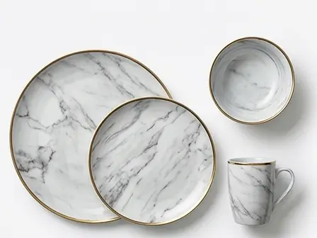 Elegant white marble pattern melamine tableware from China with gold rim detailing, featuring dinner plates, a bowl, and a mug.