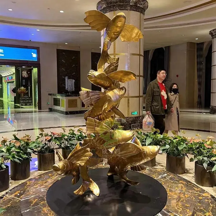 A vertical brass sculpture of multiple koi fish leaping upward, representing Custom Sculptures from China as a decorative centerpiece in a luxury hotel lobby.