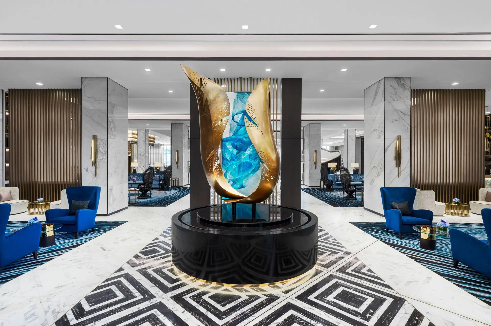 A large abstract gold and blue glass centerpiece from a collection of Custom Sculptures from China displayed in a luxury hotel lobby