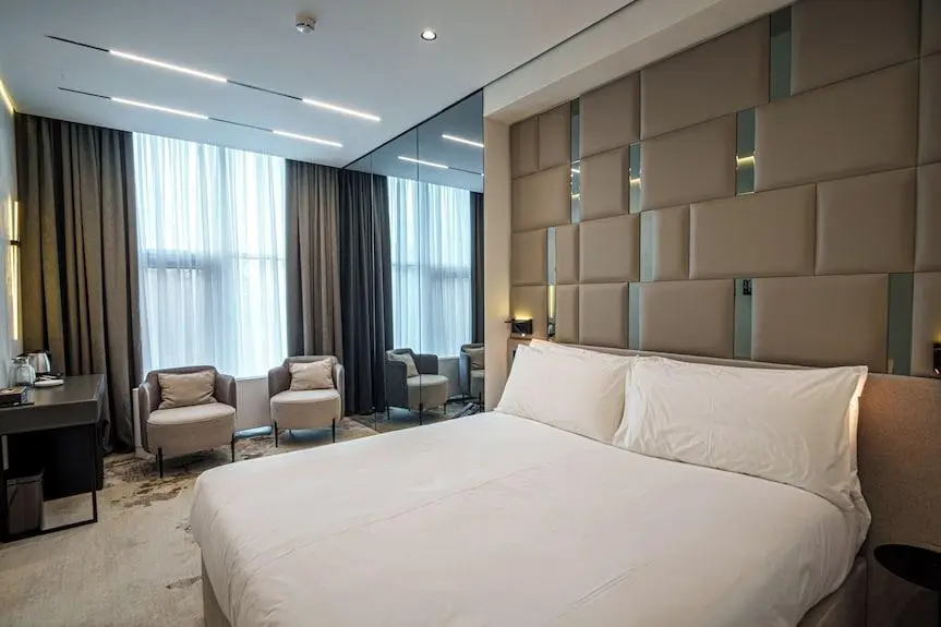 Geometric Upholstered Chinese Headboard with Mirror Accents Modern geometric upholstered Chinese headboard with square paneling and mirror strips in a luxury hotel suite