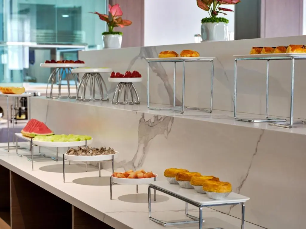 Buffet Risers China for Hotel Displays Modern stainless steel and white display buffet risers China holding pastries, fruit, and platters on a multi-tiered hotel counter setup.