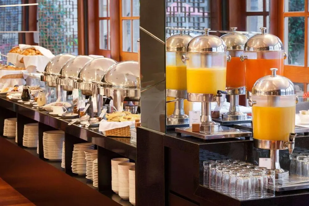 Professional Buffet Equipment China for Hotels and Restaurants High-end commercial buffet equipment China setup showcasing stainless steel chafing dishes, beverage dispensers, organized tableware, and glassware in a luxury hotel dining hall.